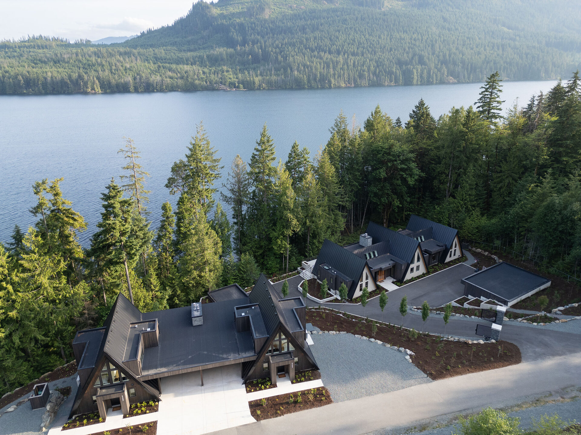 Aerial over the three cabins with Cowichan Lake and the mountains beyond