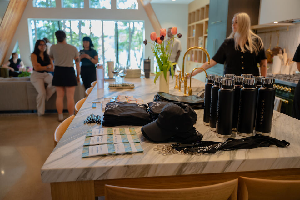 Company welcome gifts, water bottles, caps and notebooks, laid out on the marble island as guests arrive