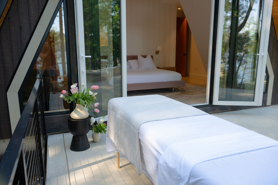A massage table dressed in white on the deck outside the bedroom, tulips beside it