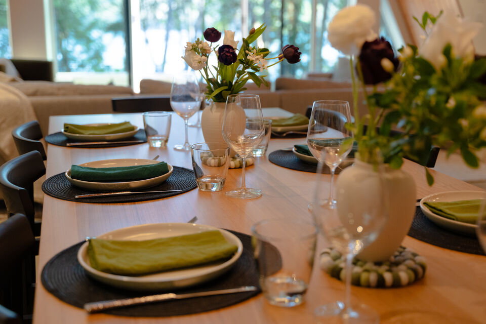 Green linen place settings and spring flowers on the long oak table