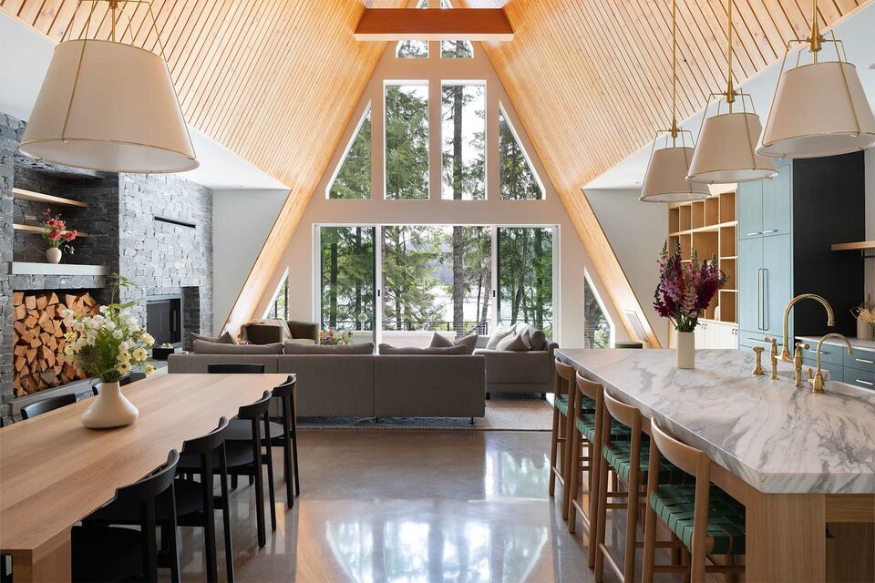 Main Cabin kitchen island and dining area beneath the soaring wood A-frame ceiling with forest-view windows