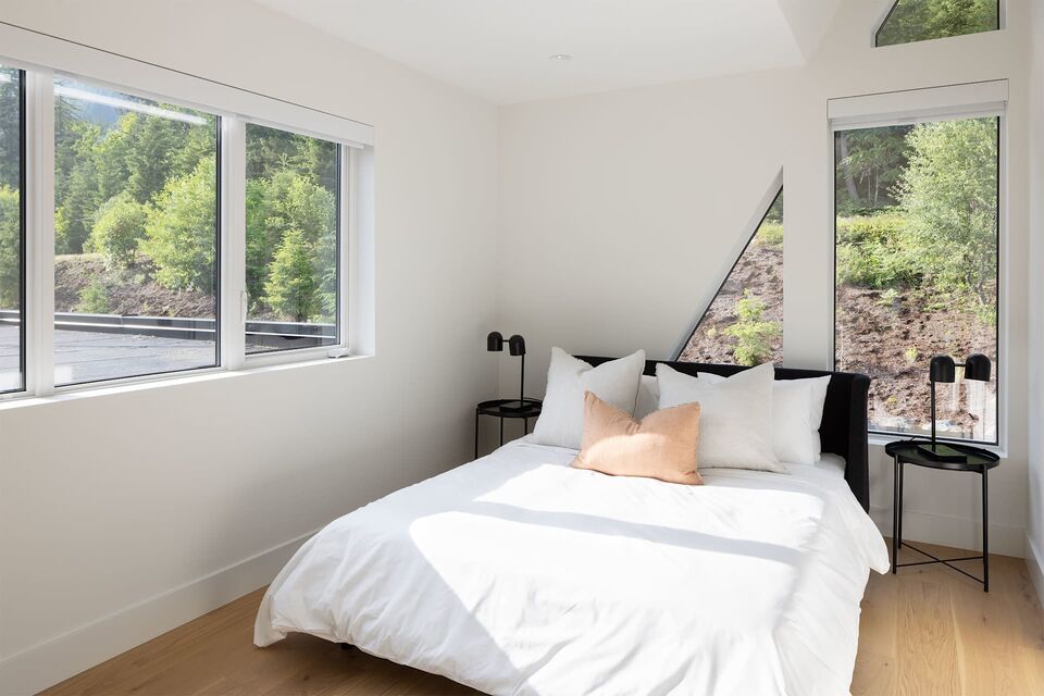 Cabin 1 bedroom with white bedding and bright corner windows