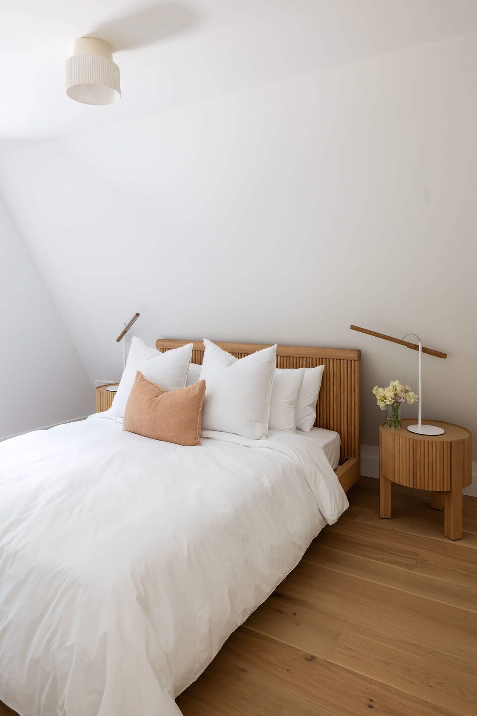 Cabin 1 bedroom with warm wood bed frame and fresh flowers