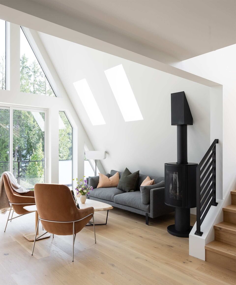 Cabin 2 lounge with leather chairs, grey sofa and wood stove under the skylight