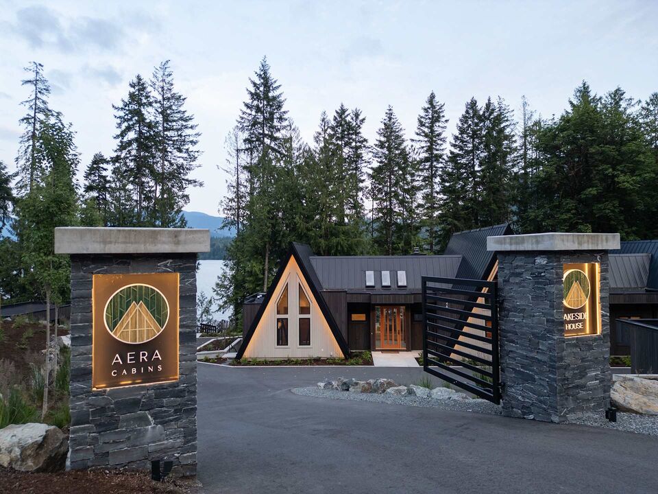 Stone entrance gate with Aera Cabins sign and A-frame cabins behind